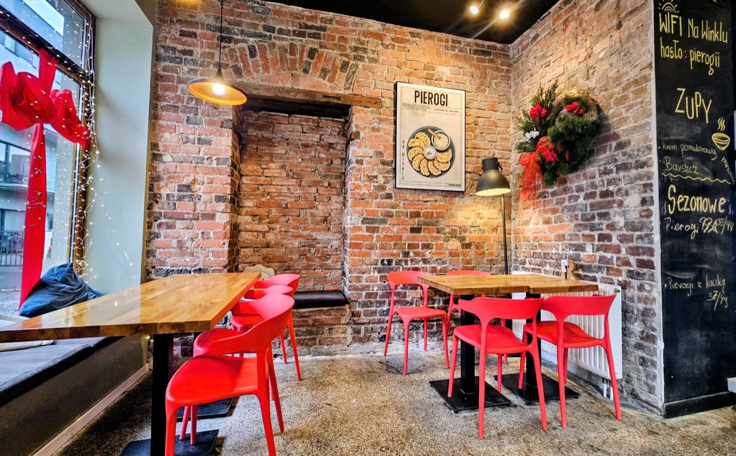 Sala Na Winklu z ceglaną ścianą, plakatem pierogi i czerwonymi krzesłami